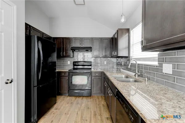 a kitchen with a refrigerator a sink and wooden cabinets