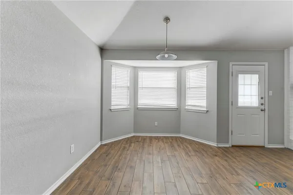 a view of an empty room with window and wooden floor