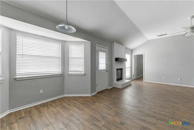 a view of an empty room with window and wooden floor