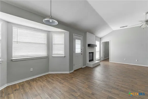 a view of an empty room with window and wooden floor