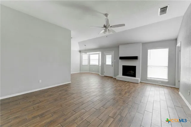 wooden floor fireplace and windows in an empty room
