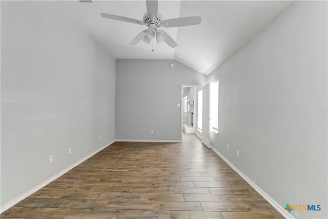 a view of an empty room with window and a chandelier fan