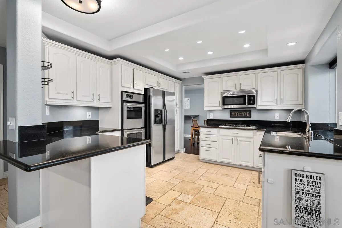 10145 Greenleaf Road Spring Valley, CA 91977 - Photo 23 of 37 a kitchen with stainless steel appliances granite countertop a refrigerator a stove a sink a microwave and white cabinets