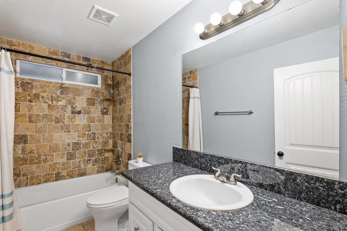 10145 Greenleaf Road Spring Valley, CA 91977 - Photo 30 of 37 a bathroom with a granite countertop sink toilet a mirror and shower