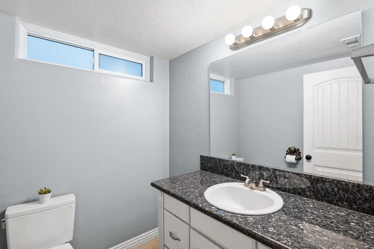 10145 Greenleaf Road Spring Valley, CA 91977 - Photo 31 of 37 a bathroom with a granite countertop sink and a mirror