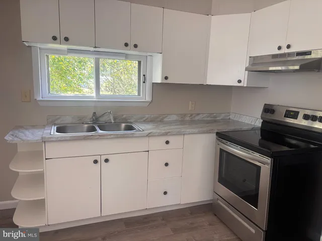 a kitchen with granite countertop white cabinets and a sink