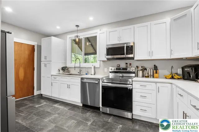 a kitchen with granite countertop white cabinets and stainless steel appliances