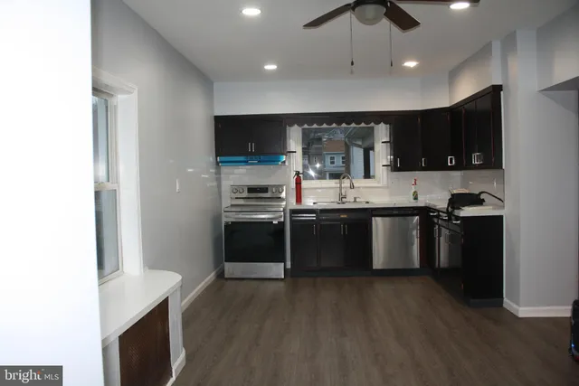 a kitchen with stainless steel appliances kitchen island granite countertop a stove a sink and a refrigerator with wooden floor