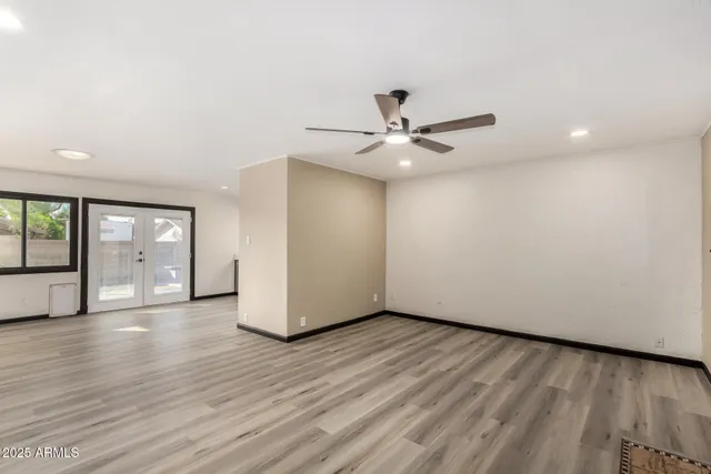 a view of an empty room with wooden floor and a ceiling fan