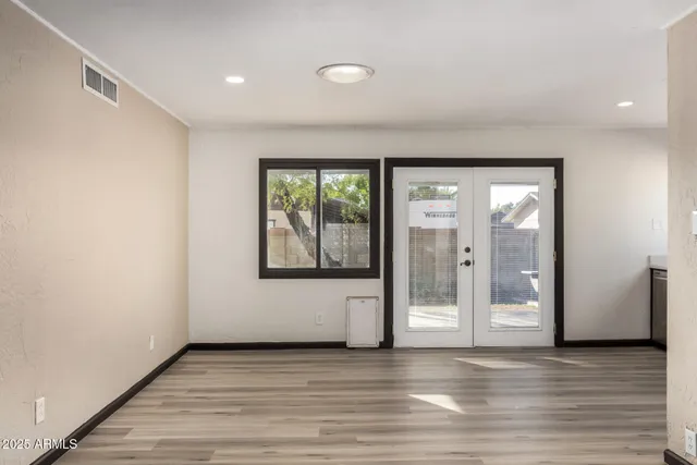a view of an empty room with wooden floor and a window