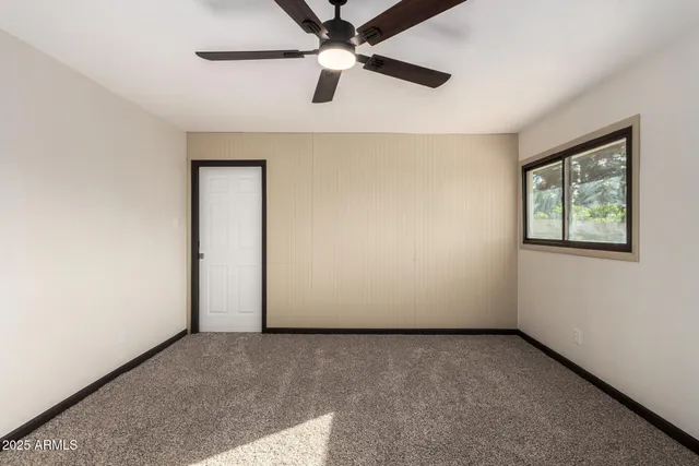 an empty room with a window and a ceiling fan