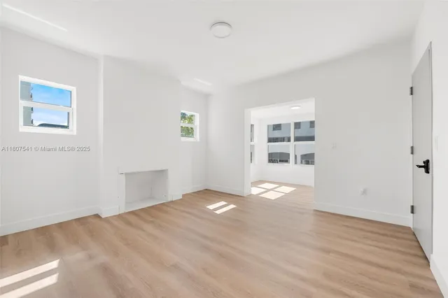 a view of an empty room with wooden floor and windows