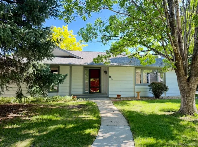 a view of a house with a small yard plants and a large tree