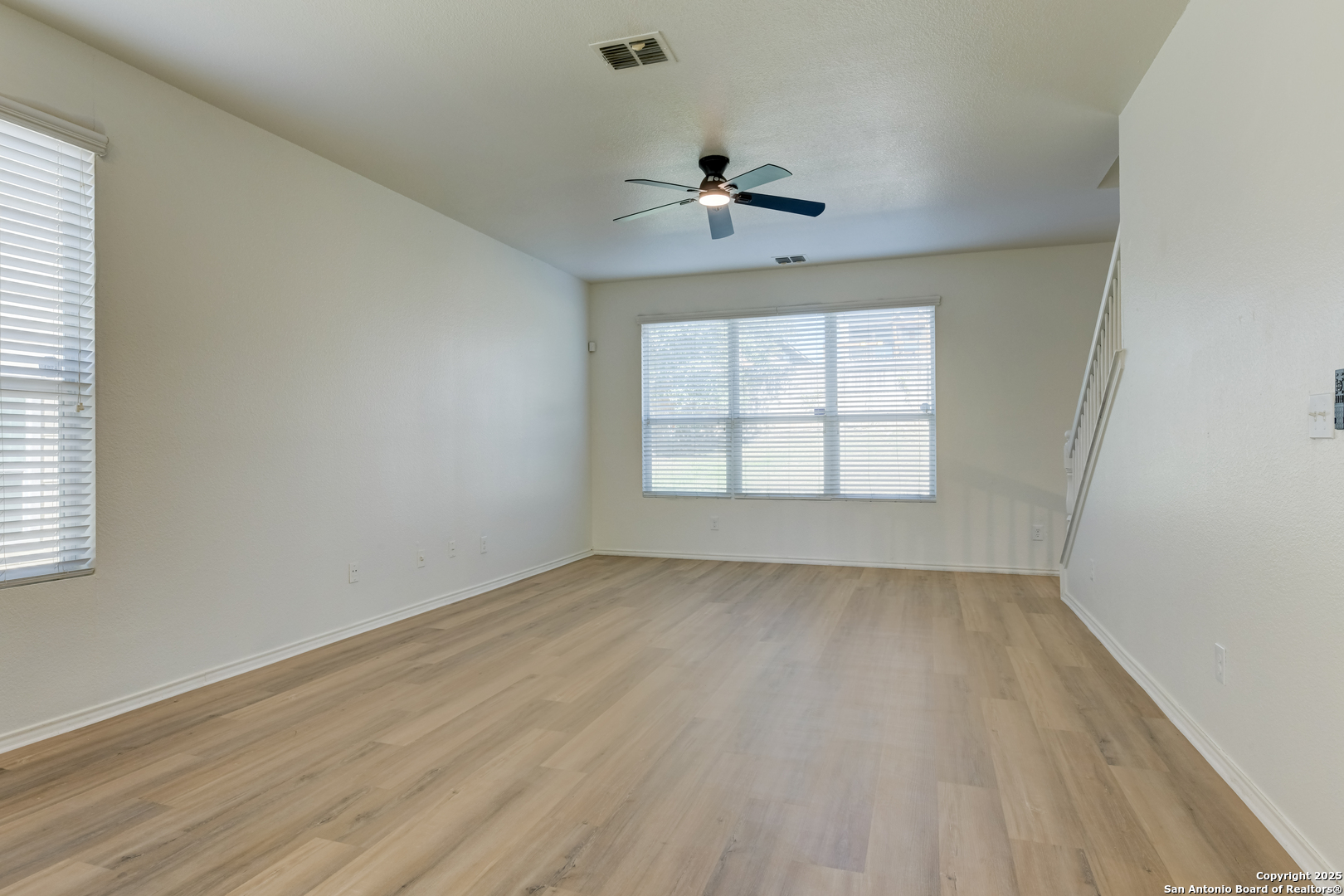 9447 Copper Mist Converse, TX 78109 - Photo 4 of 25 an empty room with wooden floor chandelier fan and windows