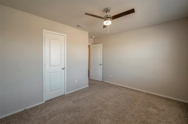 an empty room with a fan & a ceiling fan