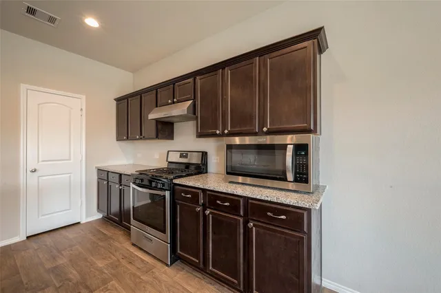 a kitchen with stainless steel appliances a stove a microwave and a sink