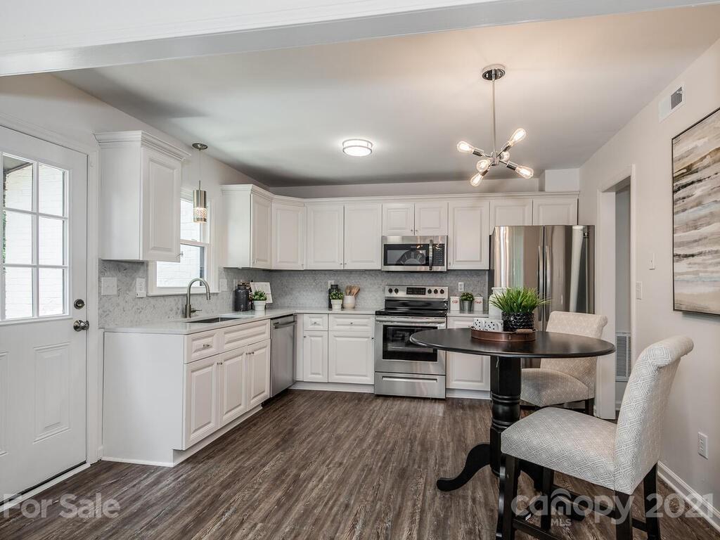 5024 Rea Road Charlotte, NC 28226 - Photo 8 of 19 a kitchen with stainless steel appliances kitchen island granite countertop a stove a sink dishwasher a refrigerator white cabinets and wooden floor
