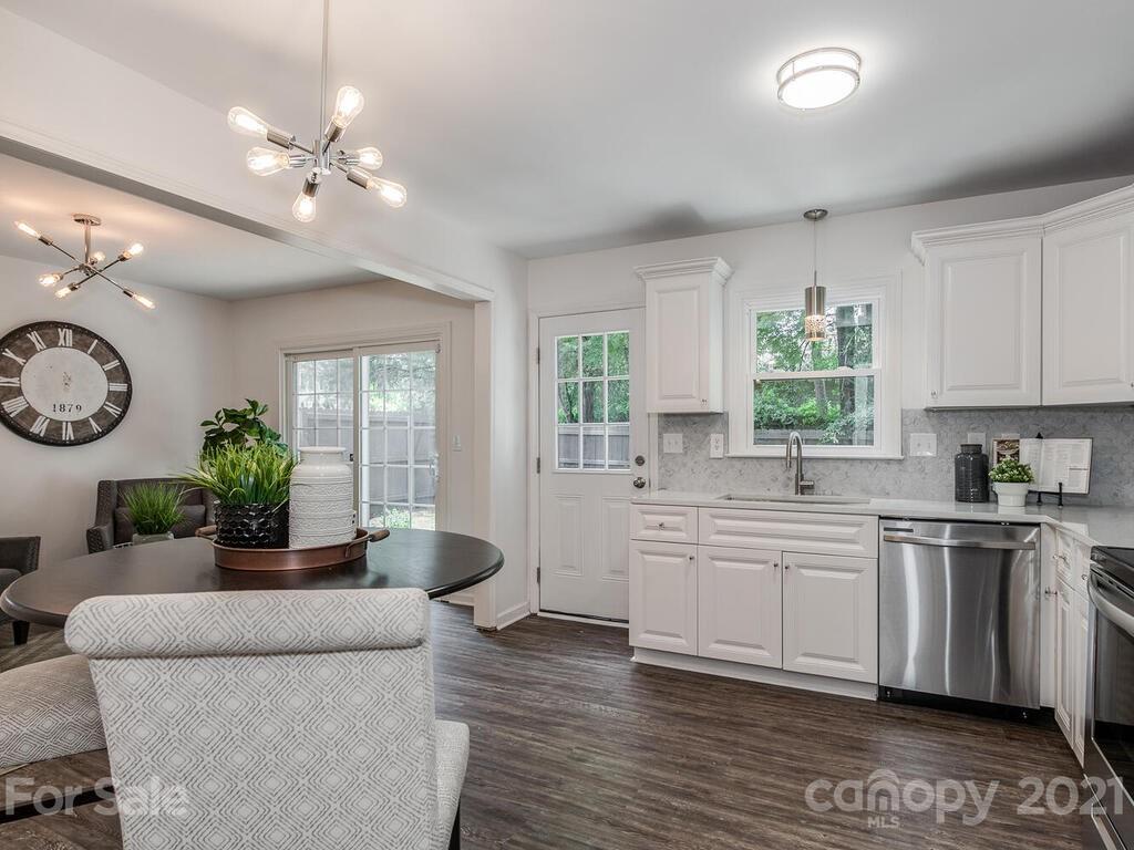 5024 Rea Road Charlotte, NC 28226 - Photo 9 of 19 a kitchen with stainless steel appliances granite countertop a stove top oven a sink dishwasher a dining table and chairs with wooden floor
