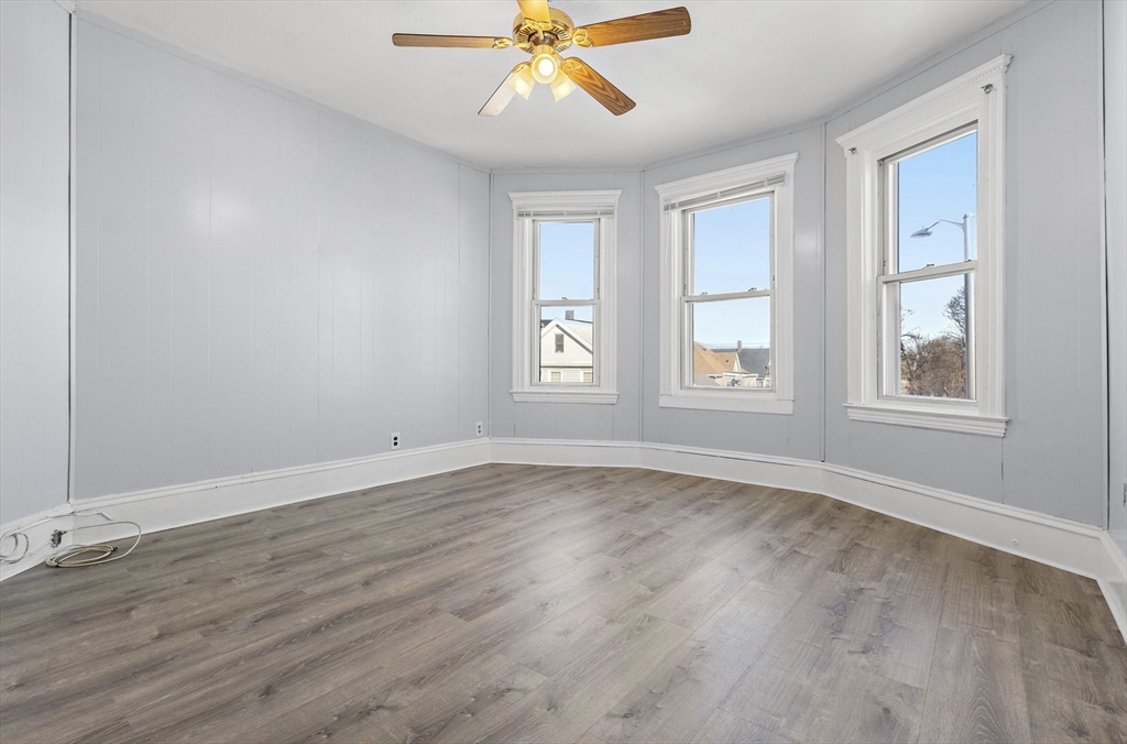 403 Ferry Street, Unit 2 Malden, MA 02148 - Photo 2 of 17 an empty room with wooden floor windows and fan
