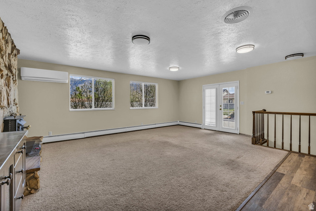 10705 Green Ridge Drive Sandy, UT 84070 - Photo 9 of 55 Unfurnished living room with a textured ceiling, french doors, healthy amount of natural light, a baseboard heating unit, and carpet