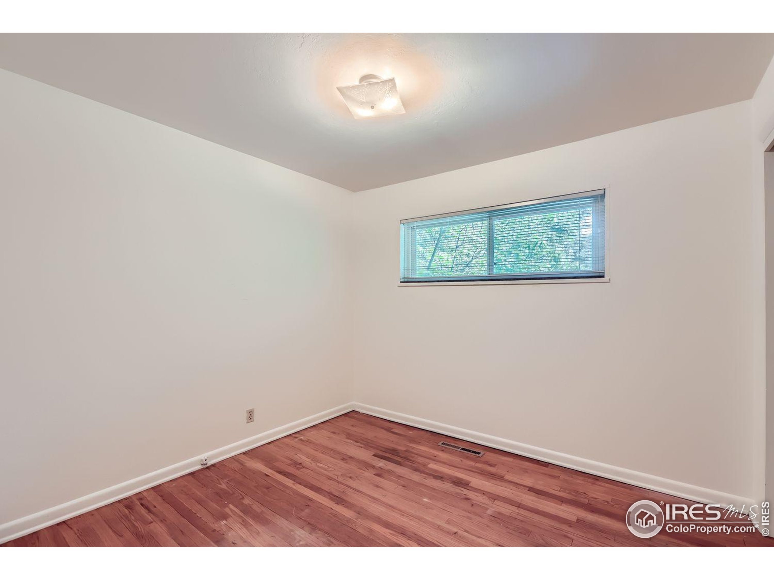 1517 Crestmore Place Fort Collins, CO 80521 - Photo 22 of 28 an empty room with wooden floor and windows
