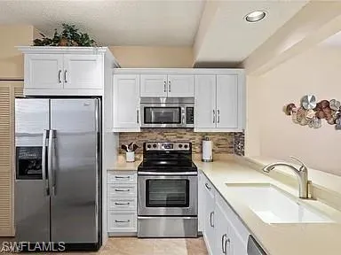 a kitchen with white cabinets and stainless steel appliances