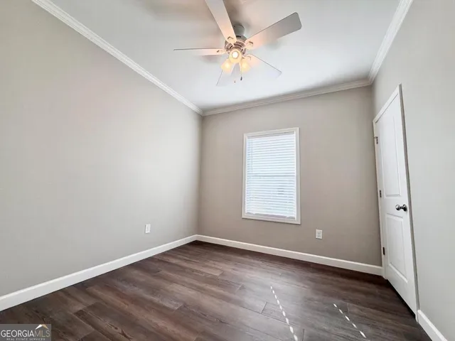 an empty room with wooden floor and ceiling fan