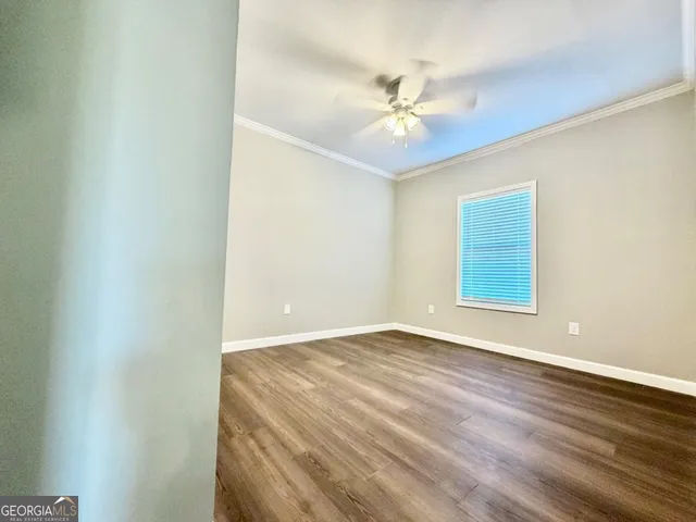 an empty room with wooden floor chandelier fan and windows