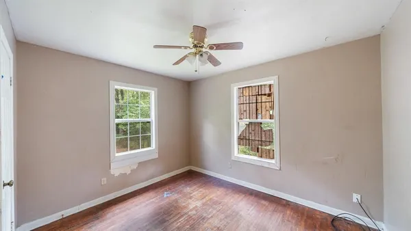 a view of an empty room with a window and wooden floor