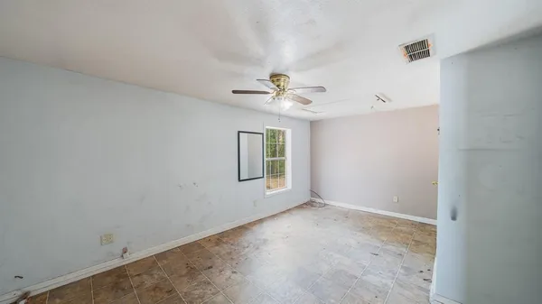 an empty room with a window and a ceiling fan