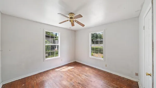 a view of an empty room with a window and wooden floor