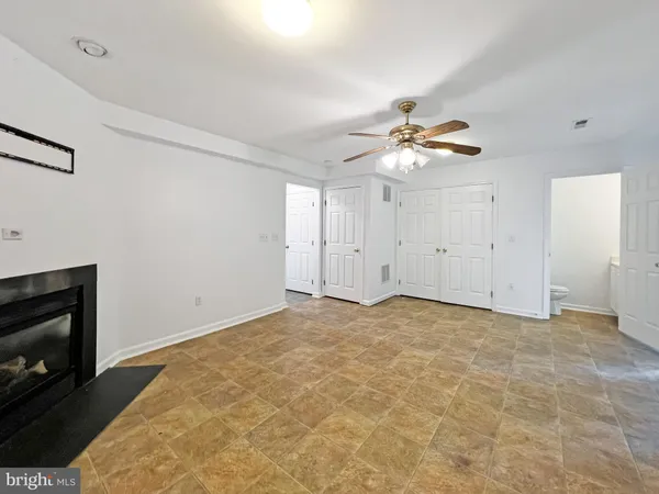 a view of an empty room with chandelier fan and fireplace