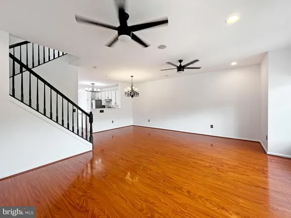 an empty room with wooden floor fan and windows