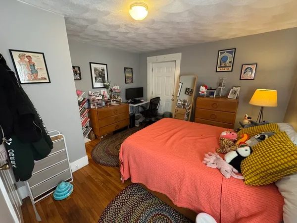 a bedroom with bed and a lamp on dresser