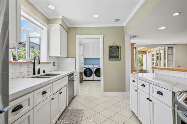 a large white kitchen with a sink and a large window
