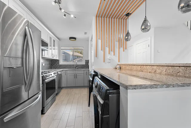 a kitchen with stainless steel appliances granite countertop a sink a stove and a refrigerator