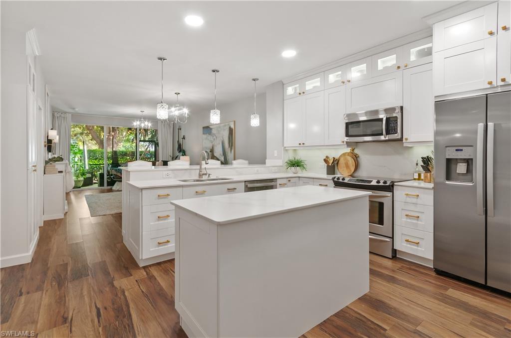 10020 Heather Lane, Unit 901 Naples, FL 34119 - Photo 12 of 34 a kitchen with stainless steel appliances kitchen island a refrigerator sink and wooden floor