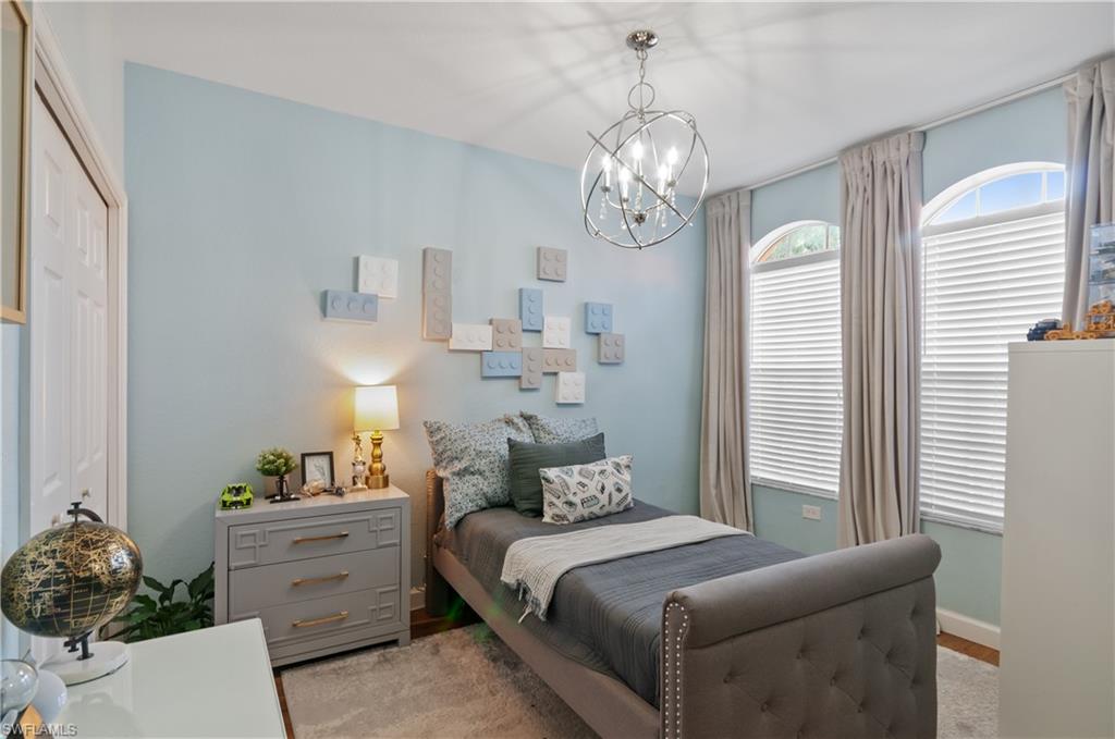 10020 Heather Lane, Unit 901 Naples, FL 34119 - Photo 16 of 34 a bedroom with a bed and a chandelier
