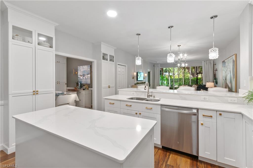 10020 Heather Lane, Unit 901 Naples, FL 34119 - Photo 21 of 34 a large white kitchen with a large island oven a sink stainless steel appliances and cabinets