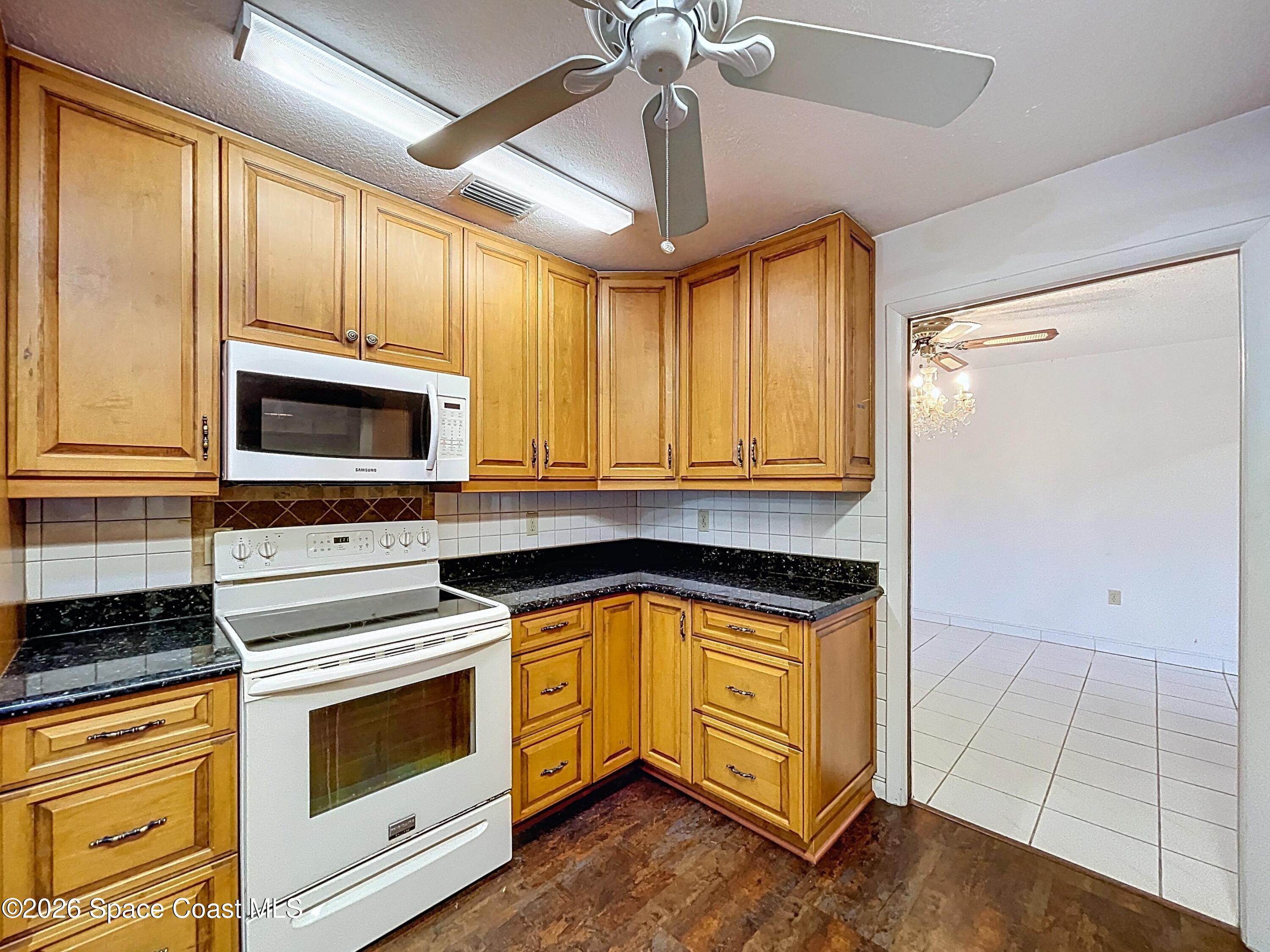 9591 128th Terrace North Largo, FL 33773 - Photo 32 of 90 a kitchen with granite countertop a stove a sink and a microwave