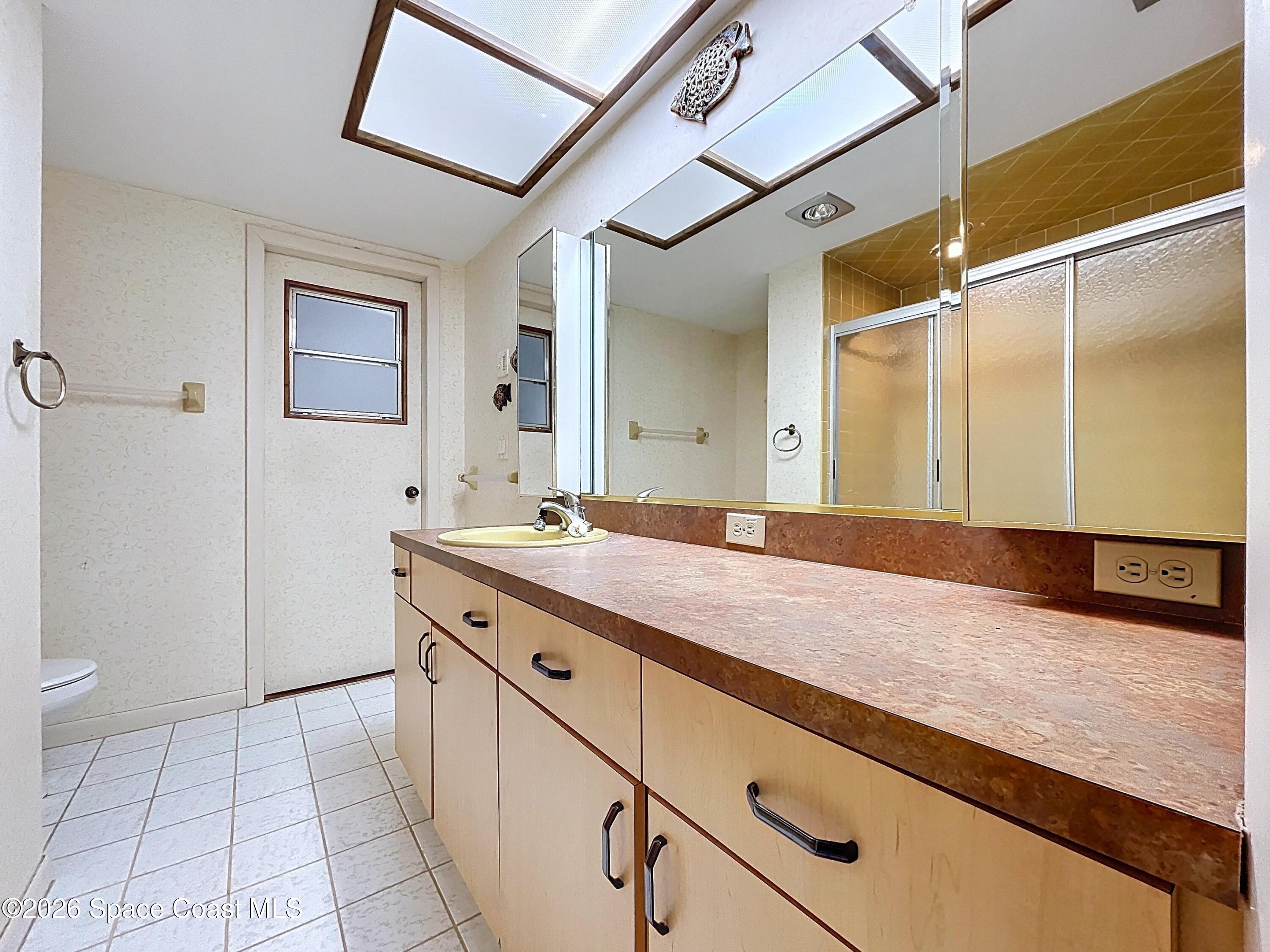 9591 128th Terrace North Largo, FL 33773 - Photo 51 of 90 a spacious bathroom with a granite countertop sink a toilet a mirror and shower