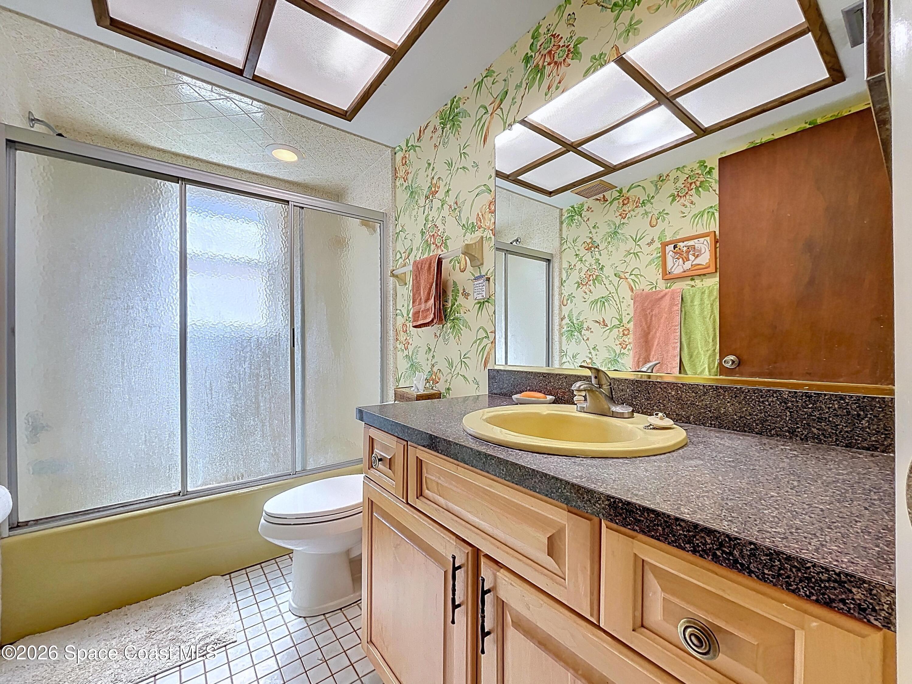 9591 128th Terrace North Largo, FL 33773 - Photo 62 of 90 a bathroom with a granite countertop sink a toilet a mirror and shower