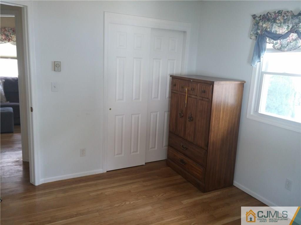 63 Enfield Road Colonia, NJ 07067 - Photo 14 of 17 an empty room with wooden floor cabinet and windows