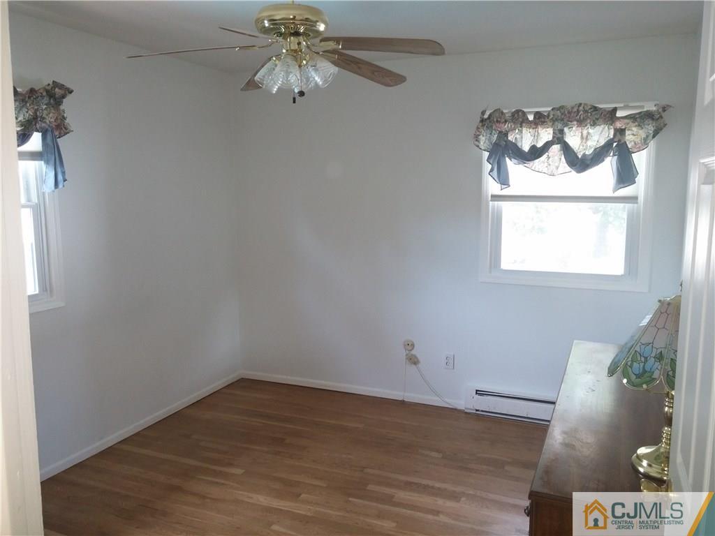 63 Enfield Road Colonia, NJ 07067 - Photo 6 of 17 an empty room with wooden floor chandelier fan and window