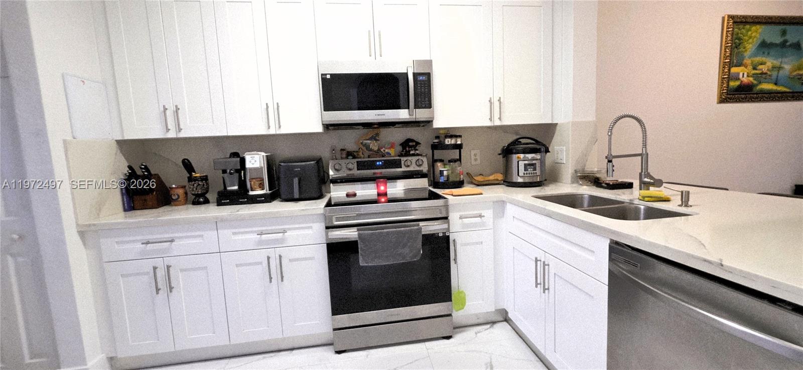 5937 Riverside Avenue Tamarac, FL 33321 - Photo 4 of 31 a kitchen with white cabinets and black appliances