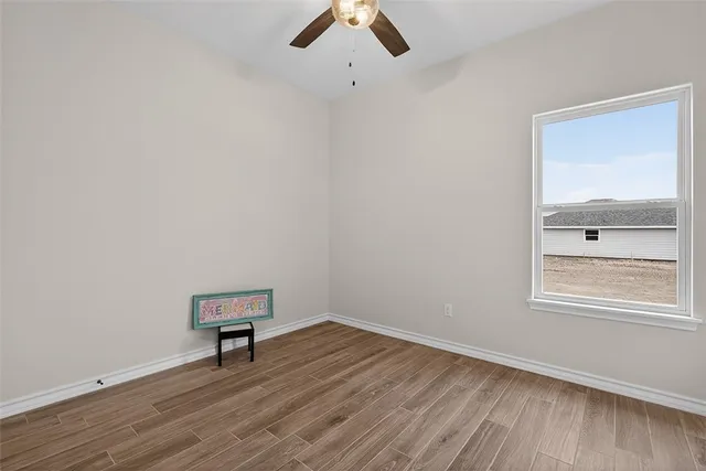 an empty room with wooden floor cabinet and windows
