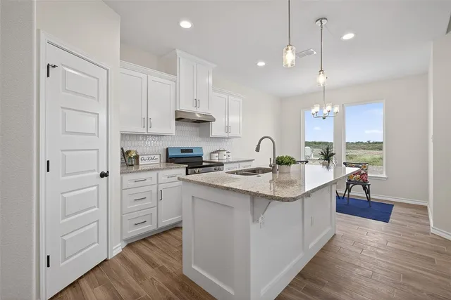 a kitchen with stainless steel appliances granite countertop a sink a stove and a refrigerator