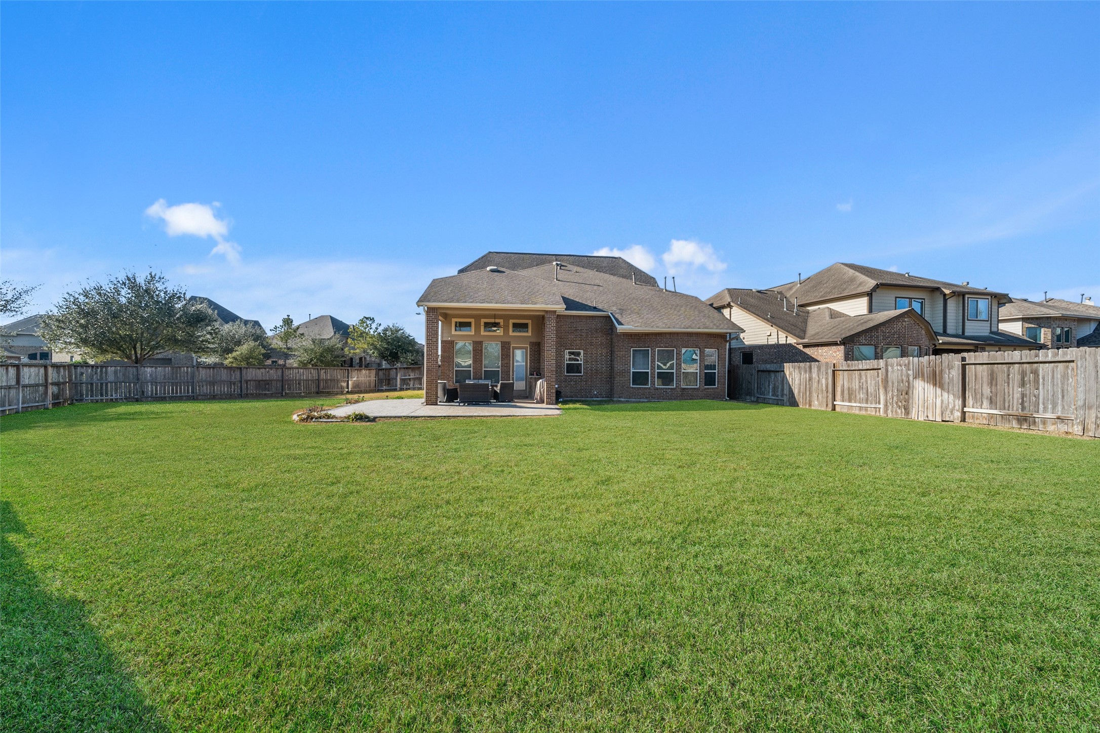 4747 Abercorn Street Rosharon, TX 77583 - Photo 33 of 46 Spacious backyard with a large, well-maintained lawn, perfect for outdoor activities. The brick house features a covered patio, ideal for relaxation and entertaining.