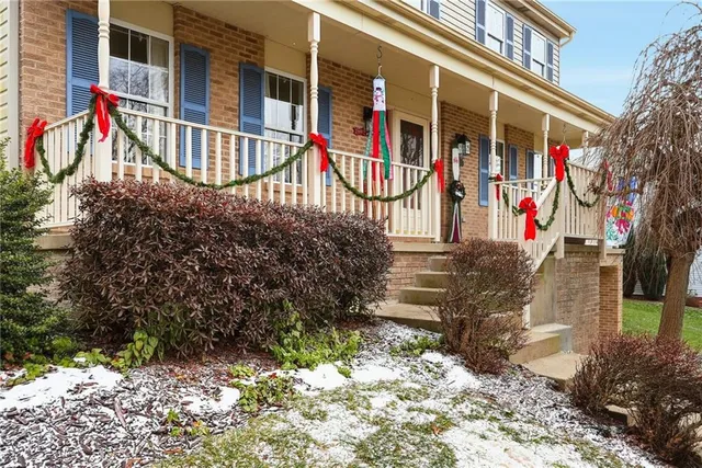a view of a brick house with large windows and flower plants