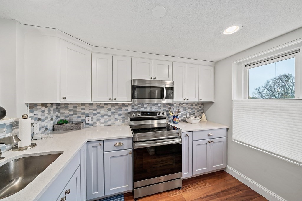 20 Rockland House Road, Unit 406 Hull, MA 02045 - Photo 9 of 39 a kitchen with cabinets stainless steel appliances and wooden floor